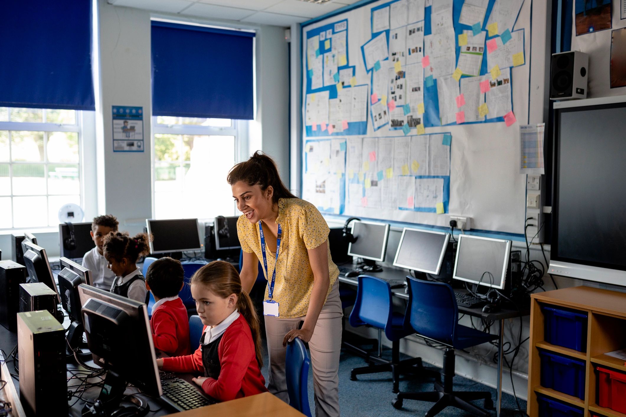 Teacher guiding students during a computer lesson