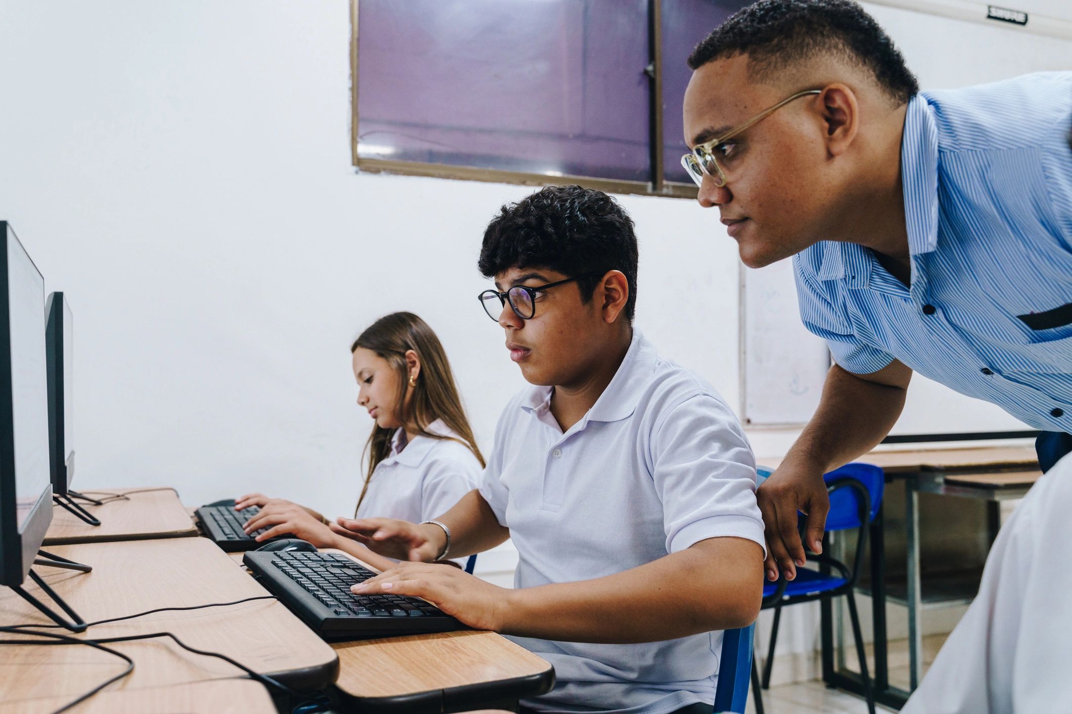 Instructor supporting a student in a computer classroom